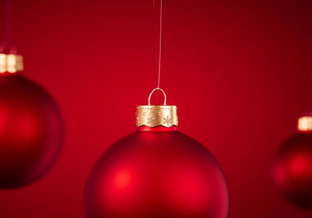 istock Christmas baubles hanging in front of red background. 1183128304