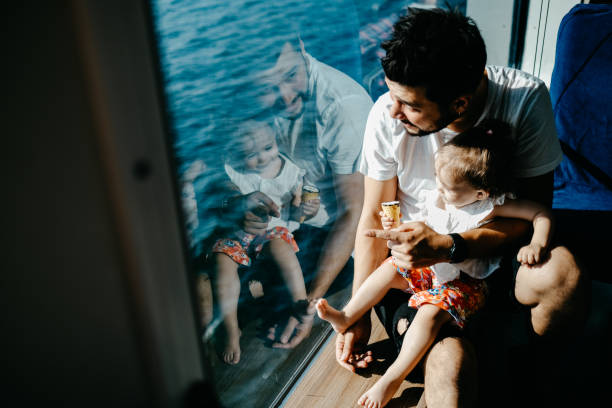 Girl traveling by ship with her father and looking through the window Girl traveling by ship with her father and looking through the window ferry stock pictures, royalty-free photos & images