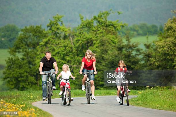 Family Of Four Riding Bicycles On A Path In A Park Stock Photo - Download Image Now - Activity, Adult, Bicycle