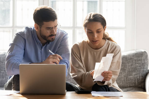 istock Serious couple calculating expenses, bills together, using laptop 1183136494