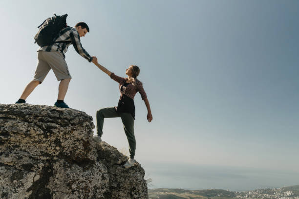 istock Trail runner, hiker or climber helping his girlfriend to climb a rock. 1183137608