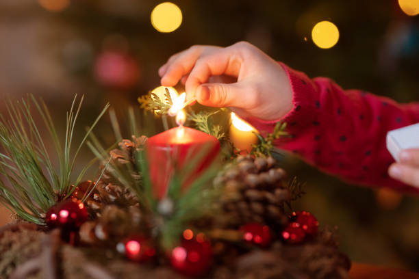 Girl is lighting candles on Advent wreath Girl is lighting candles on Advent wreath christmas decore candle stock pictures, royalty-free photos & images