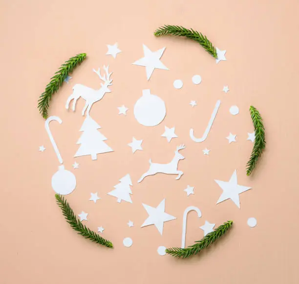 Photo of Paper Cutting and Fir Branch Leaves Forming Circle on Peach Background