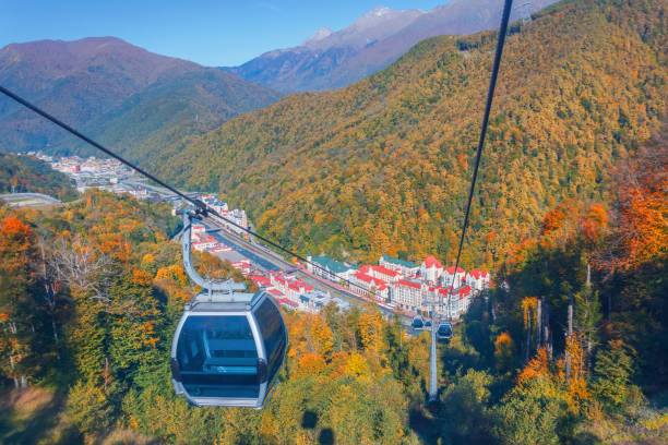 teleférico con remontes y camarotes para turistas, una vista de la ciudad y el bosque de otoño en las montañas del cáucaso. - overhead cable car summer ski lift scenics fotografías e imágenes de stock