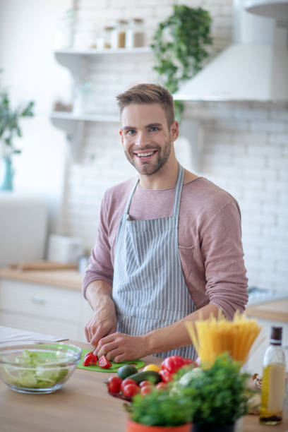 istock Handsome blue-eyed man smiling while cooking dinner 1183154034