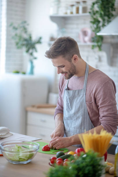 istock Smiling bearded man feeling joyful while cooking salad 1183154037