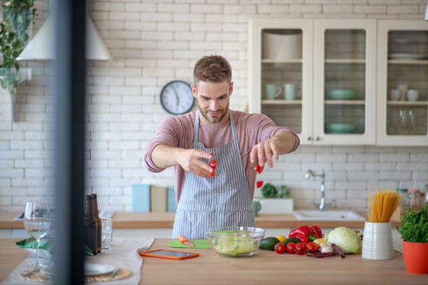 istock Bearded man putting tomatoes into salad with lettuce 1183154039