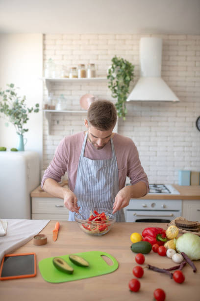 istock Dark-haired man mixing salad while cooking at the weekend 1183154074