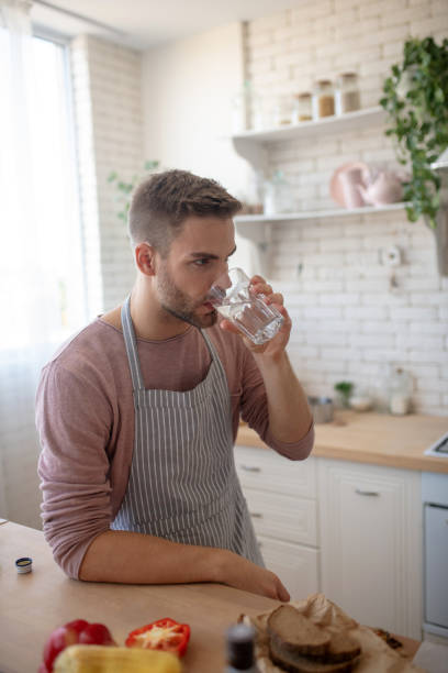 istock Man standing in the kitchen and drinking water 1183154114