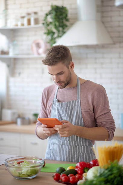 istock Man watching video on tablet and cooking at the weekend 1183154219