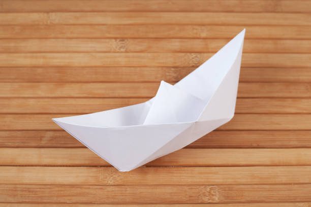 barco de origami blanco sobre fondo de madera, decoración de barco hecho a mano en primer plano de madera. artículo de exposición de arte. - nautical vessel isolated toy boat wood fotografías e imágenes de stock