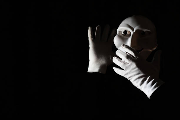 istock White scary mask on a black background with whites hand. 1183161069