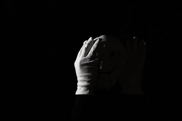 istock White scary mask on a black background with whites hand. 1183161211