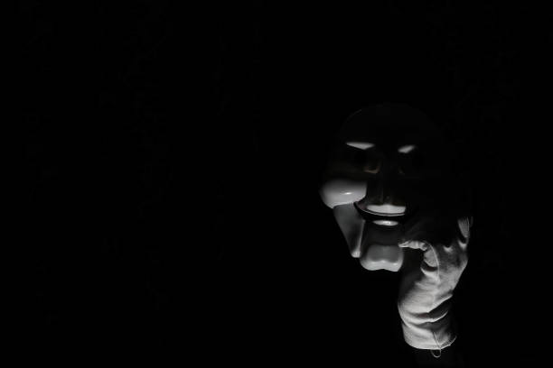 istock White scary mask on a black background with whites hand. 1183161242