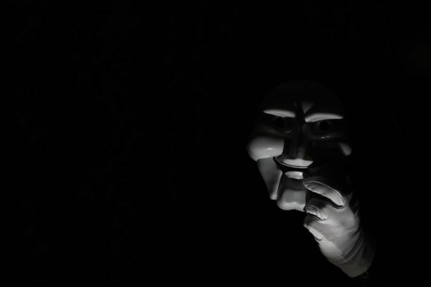 istock White scary mask on a black background with whites hand. 1183161269