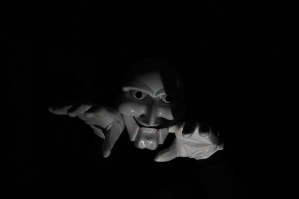 istock White scary mask on a black background with whites hand. 1183161310