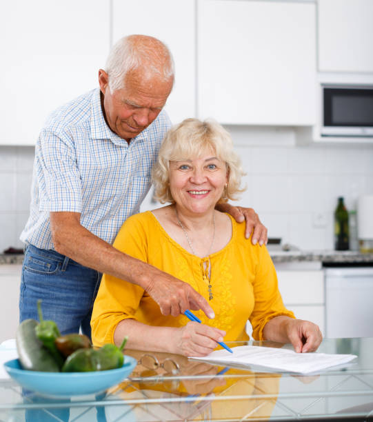 istock Smiling mature couple  in home kitchen filling up documents 1183164763