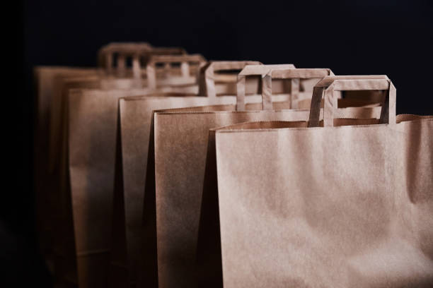коричневые бумажные пакеты на черном фоне - paper bag bag brown handle стоковые фото и изображения