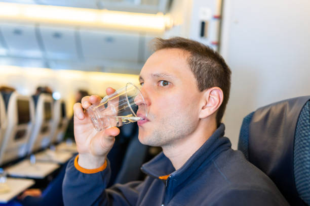 człowiek wody pitnej w plastikowym kubku podczas lotu w klasie ekonomicznej siedzenia samolotu siedzi na krześle z tła kabiny - drinking water drink men zdjęcia i obrazy z banku zdjęć