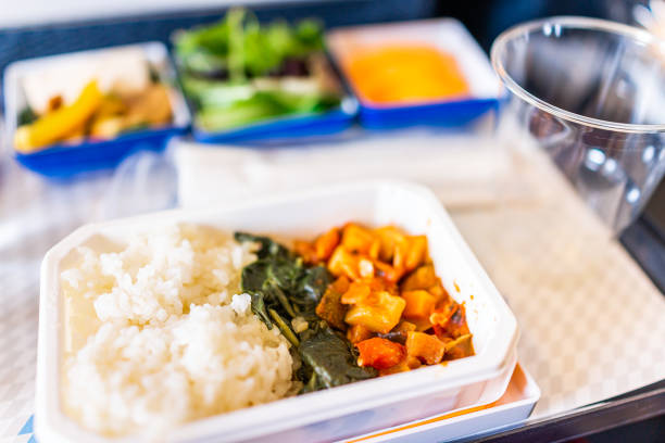 Healthy vegan asian food vgml hot meal on airplane flight tray with rice and vegetables with bokeh background of salad and plastic cup Healthy vegan asian food vgml hot meal on airplane flight tray with rice and vegetables with bokeh background of salad and plastic cup airplane food stock pictures, royalty-free photos & images