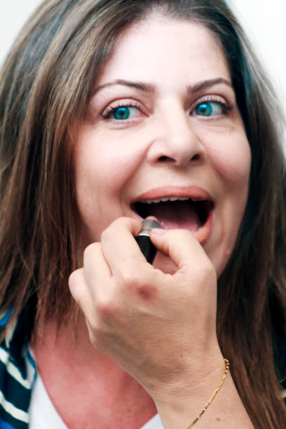 istock Beautiful mature woman putting on lipstick 1183174031