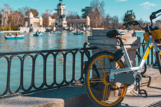 location de vélos électriques au premier plan et le parc du retiro à l'arrière-plan hors foyer. mode de vie durable - parking vélo photos et images de collection