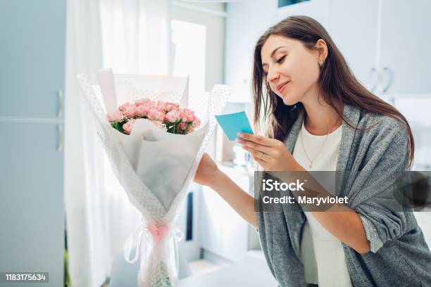 Woman Found Bouquet Of Flowers On Kitchen And Reading Card On Kitchen Surprise Present For Holiday Stock Photo - Download Image Now