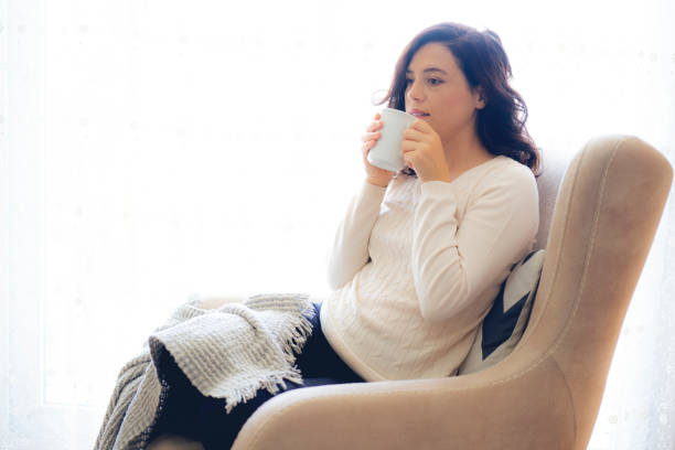 istock Woman sitting in armchair and drinking coffee 1183176090