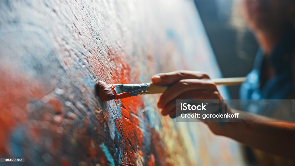 Female Artist Works on Abstract Oil Painting, Moving Paint Brush Energetically She Creates Modern Masterpiece. Dark Creative Studio where Large Canvas Stands on Easel Illuminated. Low Angle Close-up Painting - Art Product Stock Photo