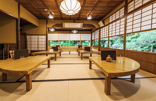 This is a photograph of the interior of a restaurant with wooden tables and floor seating in Kyoto, Japan.