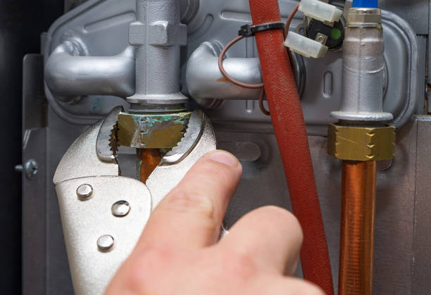 entretien d'un système de chauffage domestique. technicien avec des réparations de clé fuit tuyau d'eau chaude dans le chauffage au gaz. gros plan, mise au point sélective. - gas fitter photos photos et images de collection