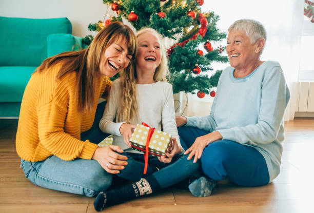 クリスマスプレゼントを開きながら楽しむ3世代家族 - grandmother giving gift child ストックフォトと画像