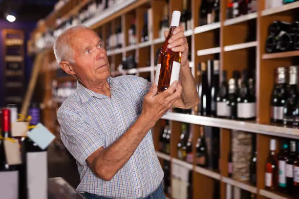 Senior man visiting winehouse in search of bottle of good wine