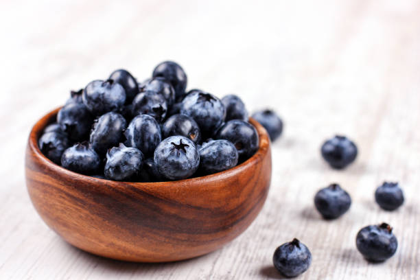 istock Fresh blueberries in a wooden bowl on white table 1183194206
