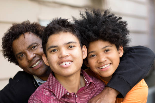 African American father hugging his two sons. Portrait of an African American father hugging his sons. developmental disability diversity stock pictures, royalty-free photos & images