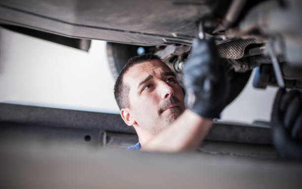 istock Auto mechanic repairer checking condition under car on vehicle lift 1183202543