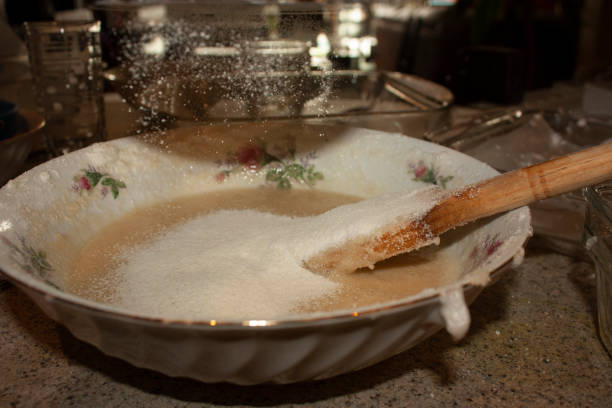 shaking sifter to sift the flour that will slowly fall on the egg whites about to nougat, in order to hold the foam of the whites key to make macarrons Cooking or making macaroni at the key point sifting flour and sugar glass over egg whites lluvia stock pictures, royalty-free photos & images