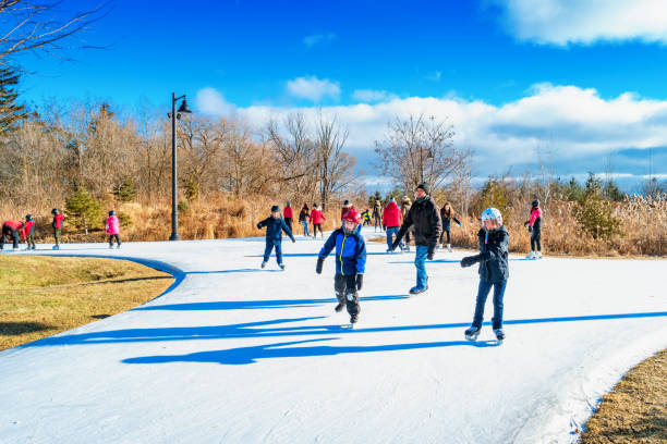 People ice skate in a park People ice skate in a park in Etobicoke, Toronto, Ontario, Canada on a sunny day. etobicoke stock pictures, royalty-free photos & images