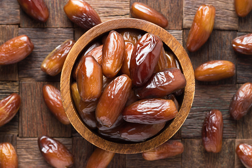 dried date fruit in bowl on wooden table background.