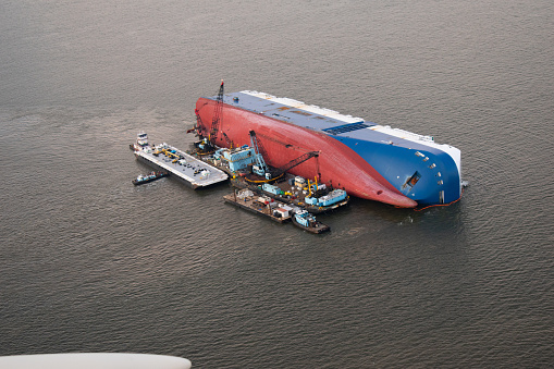 The Golden Ray cargo ship, capsized in St. Simon's Sound, Georgia. Aerial photo taken from small plane. Workers attempting to recover cargo from ship.