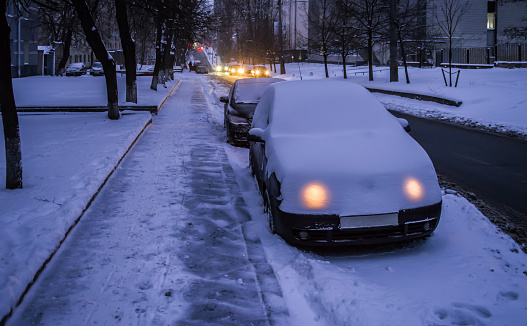 The owner of the car in the winter forgot to turn off the lights. Twilight in the city.