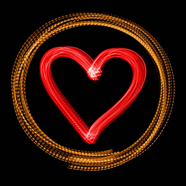 Glowing red heart in a circle made by LED light painting. Isolated on a black background.