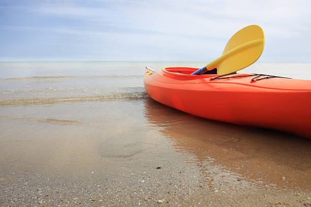 istock Orange kayak with yellow paddle anchored in the beach 118322266