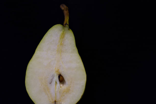 A half fresh pear lies on dark background