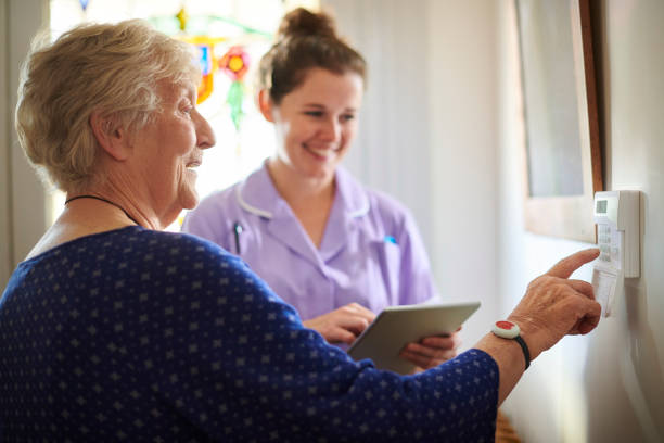 home carer showing senior woman her alarm panel home carer showing senior woman her alarm panel call button stock pictures, royalty-free photos & images