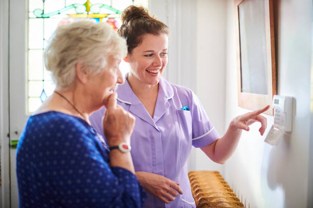 istock home carer showing senior woman her alarm panel 1183237886