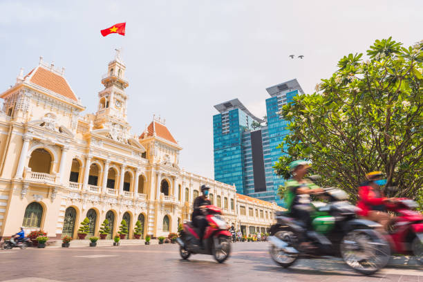 Ho Chi Minh City, Vietnam: Saigon City Hall, Vincom Center towers and colorful street traffic Ho Chi Minh City, Vietnam: Saigon City Hall, Vincom Center towers and colorful street traffic blurred in motion. Saigon downtown with its famous landmarks. Stock image with removed logos. ho chi minh city stock pictures, royalty-free photos & images