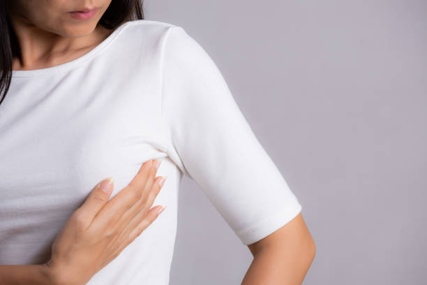 mujer revisando bultos en su pecho en busca de signos de cáncer de mama sobre fondo gris. concepto de atención médica. - human nipple fotos fotografías e imágenes de stock