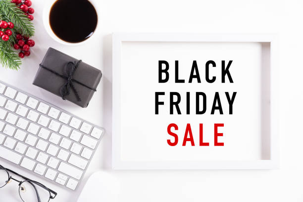 istock Black Friday Sale text on white picture frame with keyboard mouse coffee cup, gift box and Christmas tree decoration, red berries on white background. Shopping concept and black Friday composition. 1183246317