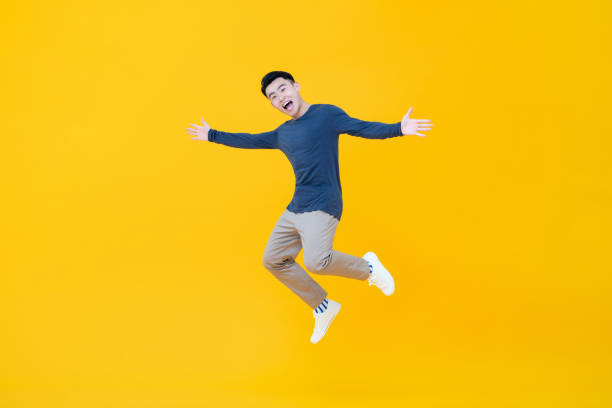 istock Asian man smiling and jumping with arms outstretched 1183254410